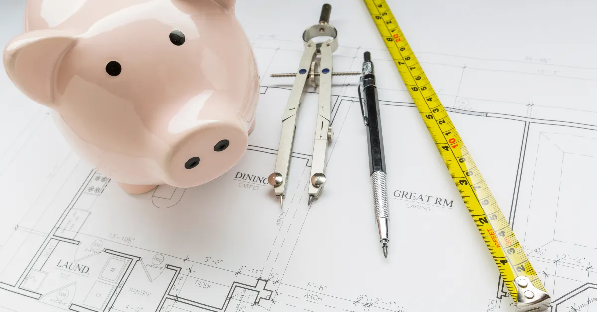 Piggy bank on construction drawings with a tape measure and compass